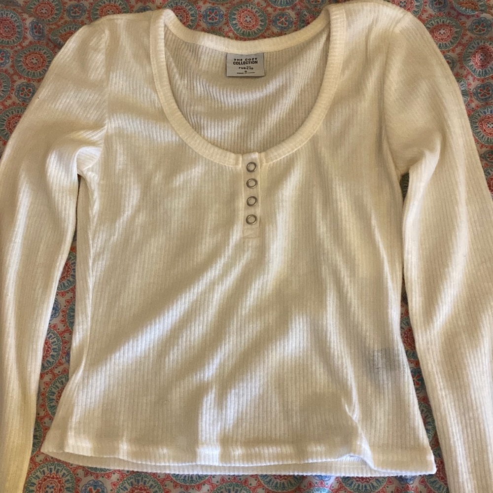 A cream long sleeve shirt with buttons about mid-level.
